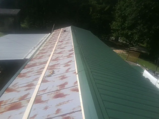 Old rusted panels beside newly installed green metal roofing — Wind Damage Roof Repair by Roofing Brothers in Doniphan
