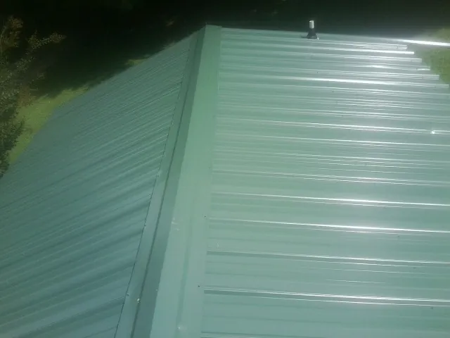 New green metal panels meeting at the ridge of a roof — Flat Roof Repair work by our crew in Doniphan