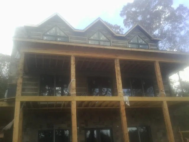 Dormers and porch framing on a large log home under construction — Roof Coating work by our crew in Doniphan