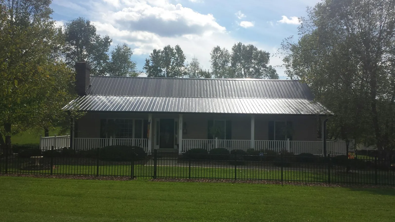 Gray metal roof on a brick ranch with a full width front porch — Gutter Guard Installation work by our crew in Doniphan