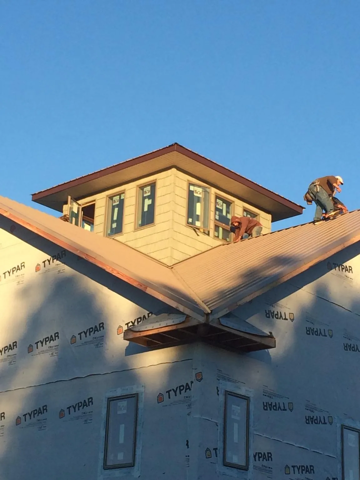 Roofers working around a rooftop cupola on a new metal roof at sunset — Roof Waterproofing in Doniphan by Roofing Brothers